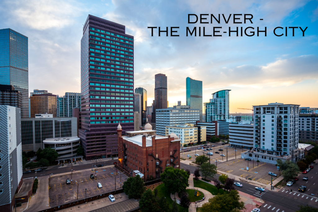 A skyline view of Denver, known as The Mile-High City, showcasing modern skyscrapers against a backdrop of the Rocky Mountains under a clear blue sky.